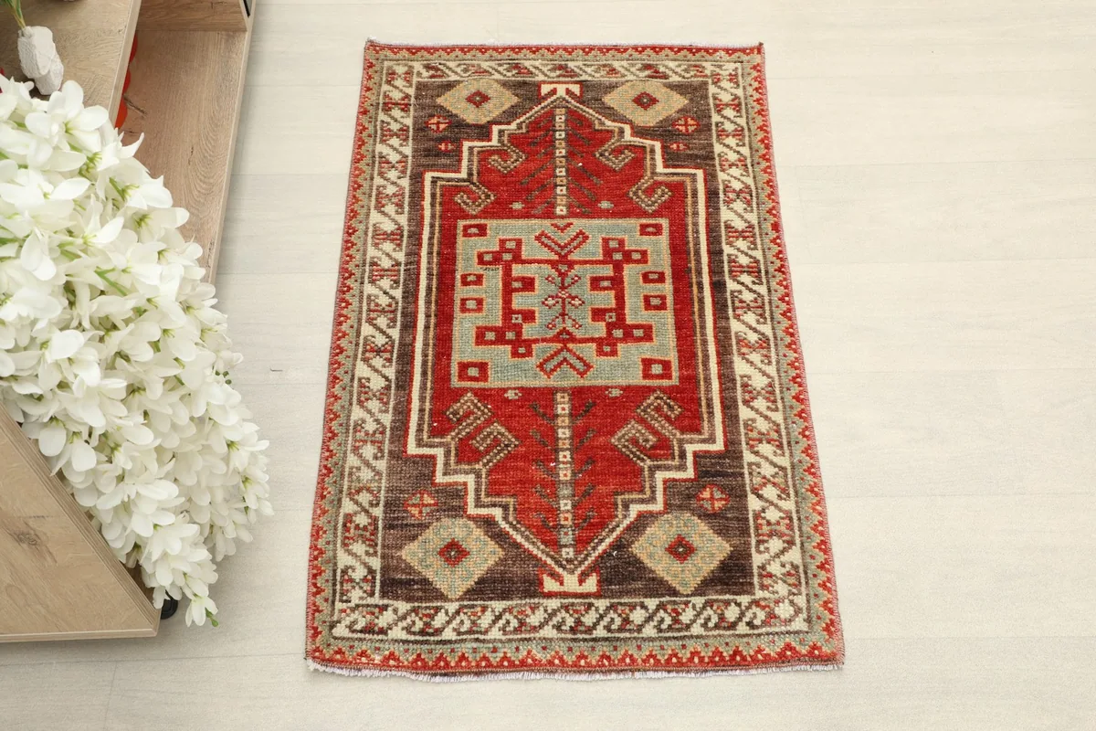 Overhead view of the hand-knotted red and blue geometric rug with brown and beige borders.