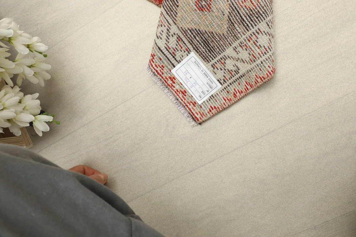View from above, showing the rug's dimensions and the label on its reverse, next to a person's foot.