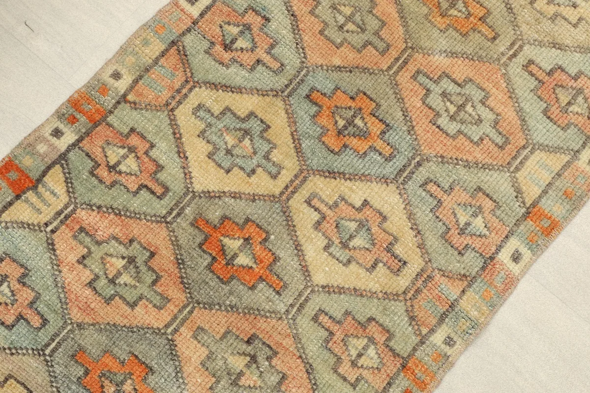 Angled view highlighting the textured wool pile and the intricate geometric motifs of the vintage rug.