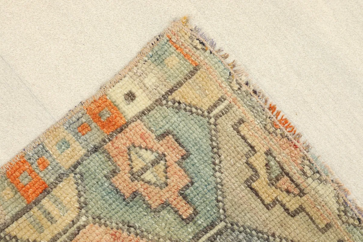 Detail view of a corner of the rug, revealing the tight knotting and color variations.