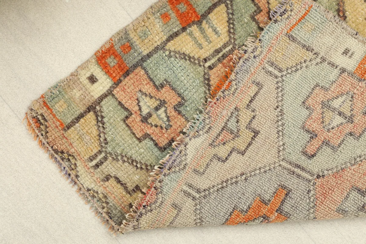 The rug folded to show the cotton foundation and the reverse side, confirming hand-knotting.