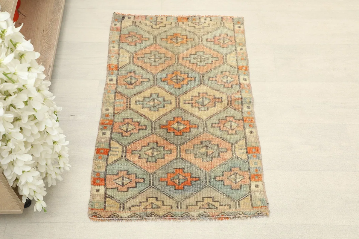 Overhead view of the small Anatolian rug, showcasing its pale blue, rose, and orange geometric design.