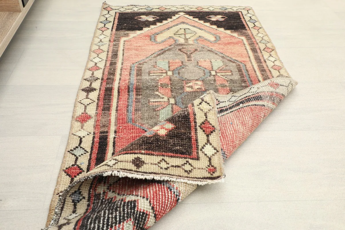 Angled view of the rug partially folded, revealing the back of the wool pile and cotton foundation.