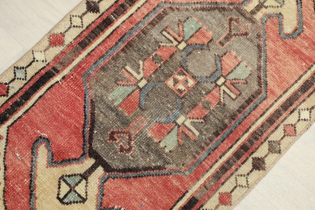 Close-up detail of the central tribal medallion in gray with blue, green, and red accents.