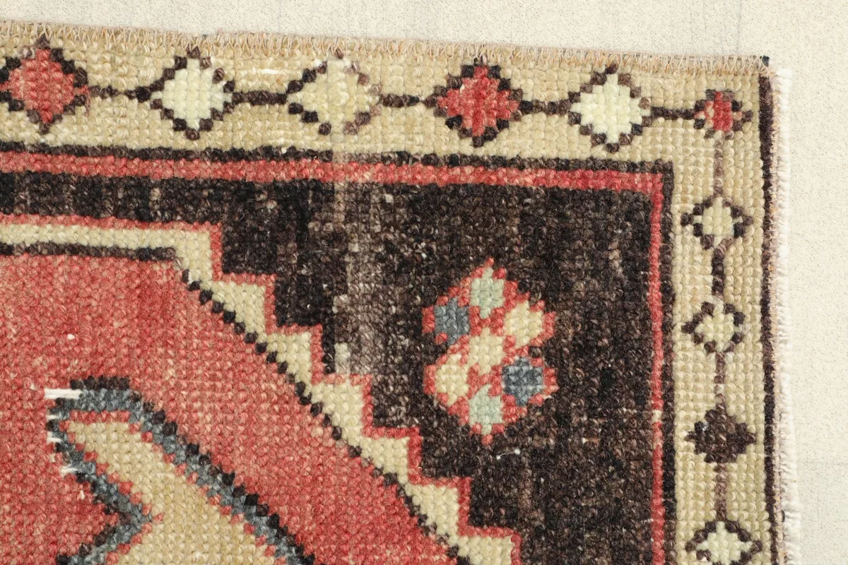 Edge detail of the rug, illustrating the black field and the beige outer border with tribal motifs.