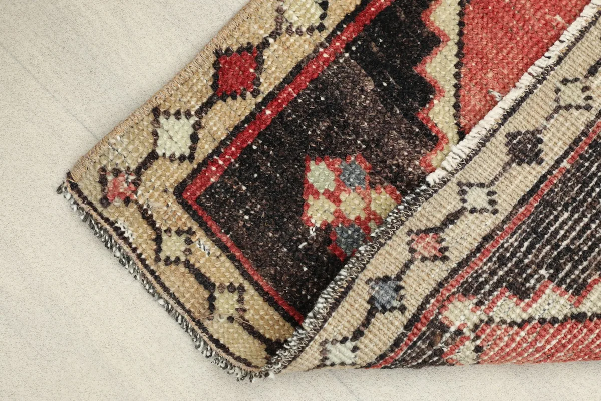 View showing the low pile and texture of the hand-knotted wool rug, with a slight fold.