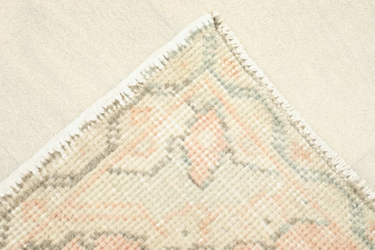 Detail of the rug's edge, showing the beige border and the hand-knotted construction.