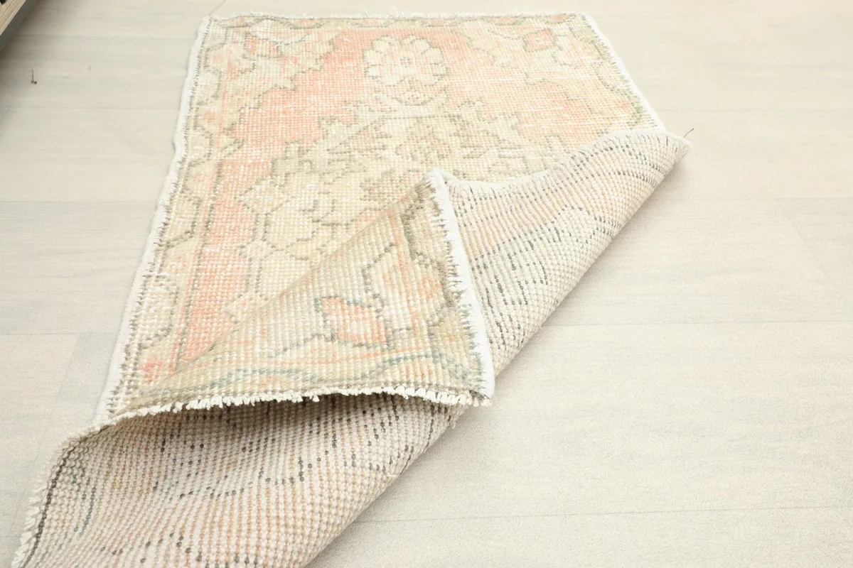 Partial fold of the rug, showing the flexibility and the texture of the vintage wool pile.