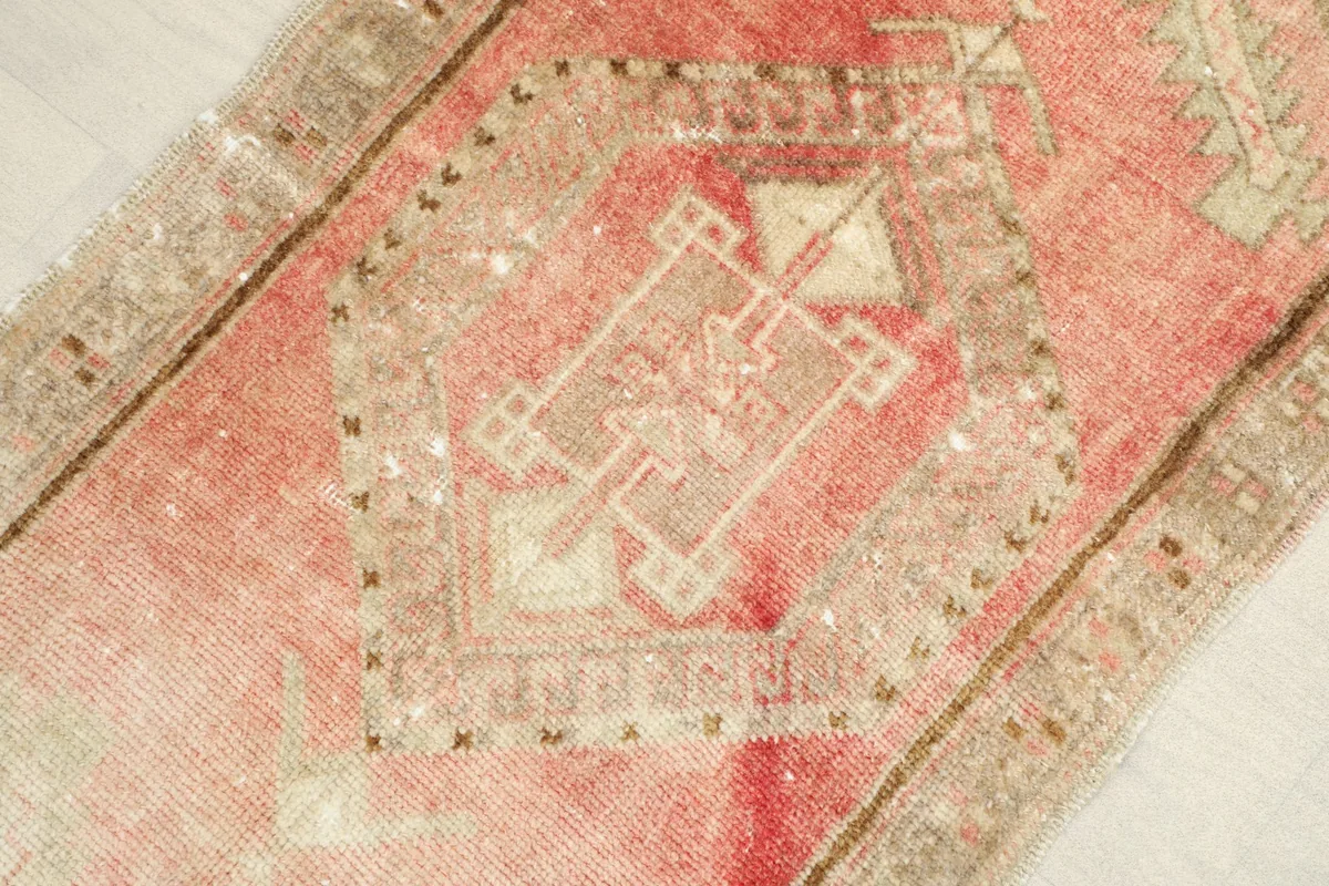 Angled close-up showing the central geometric medallion and the soft rose and beige colors of the rug.