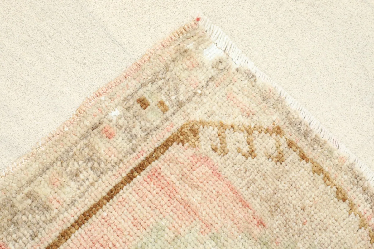 Close-up of a corner, showing the beige and brown border design and the rug's construction.