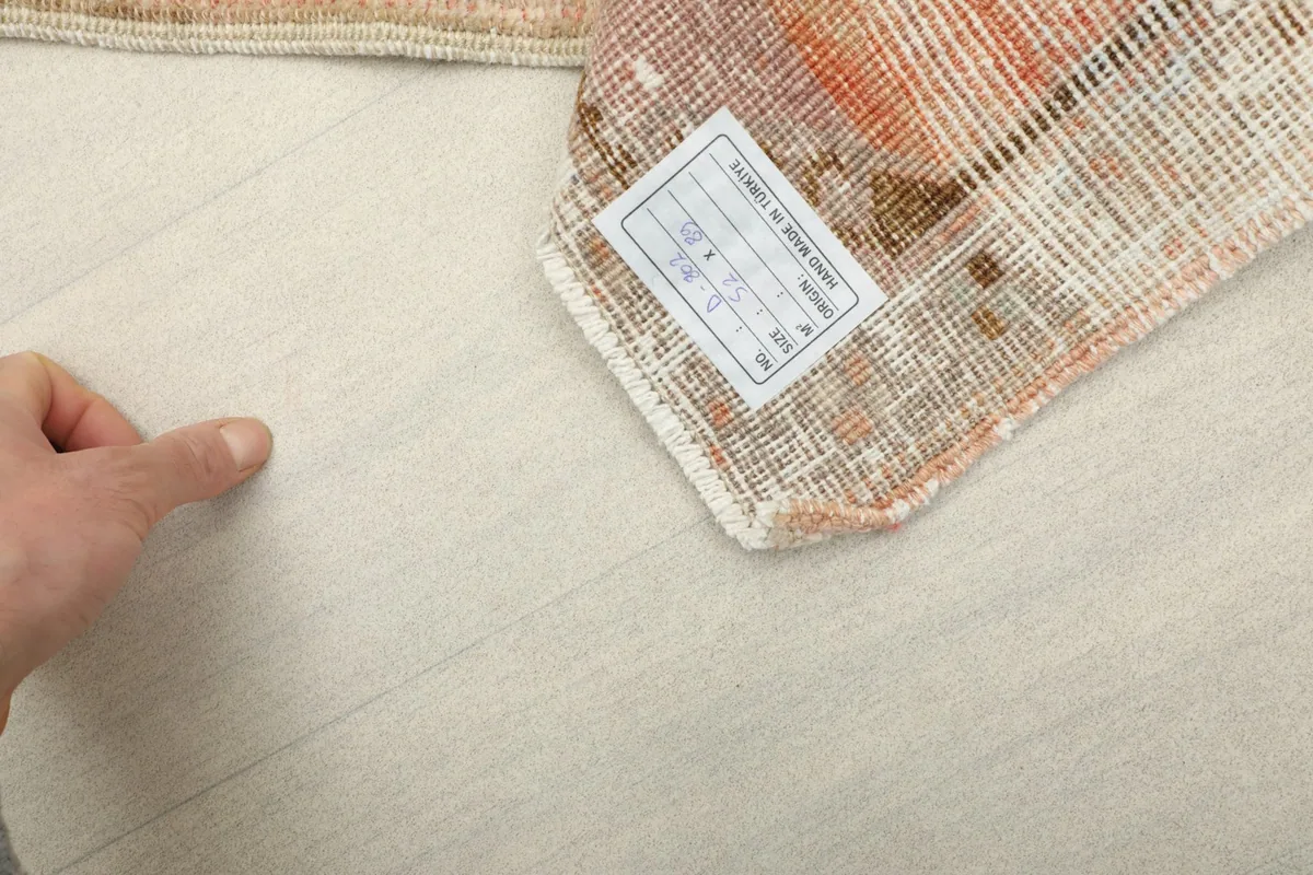 Back of the hand-knotted rug, showing the dense knotting and the cotton foundation, with a size label.