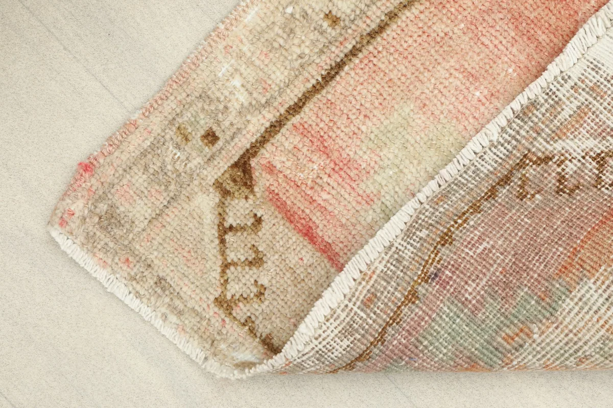 View of the rug folded back, showing the cotton foundation and the reverse side of the wool knots.
