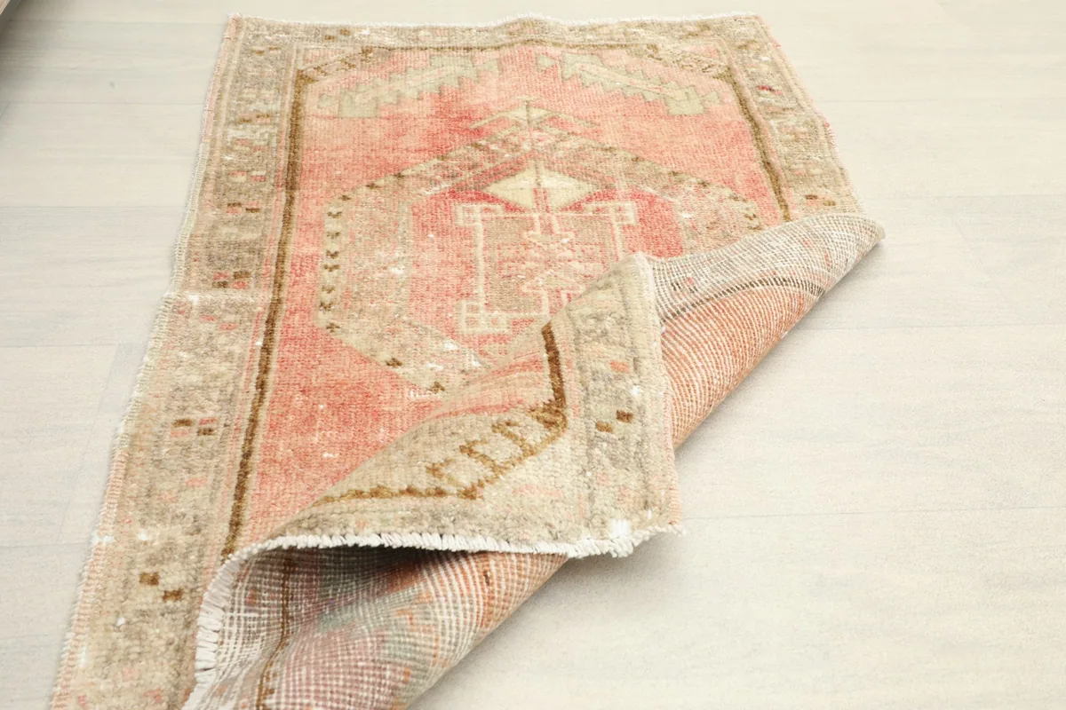 The doormat partially folded, displaying both the top surface with its pattern and the back of the rug.