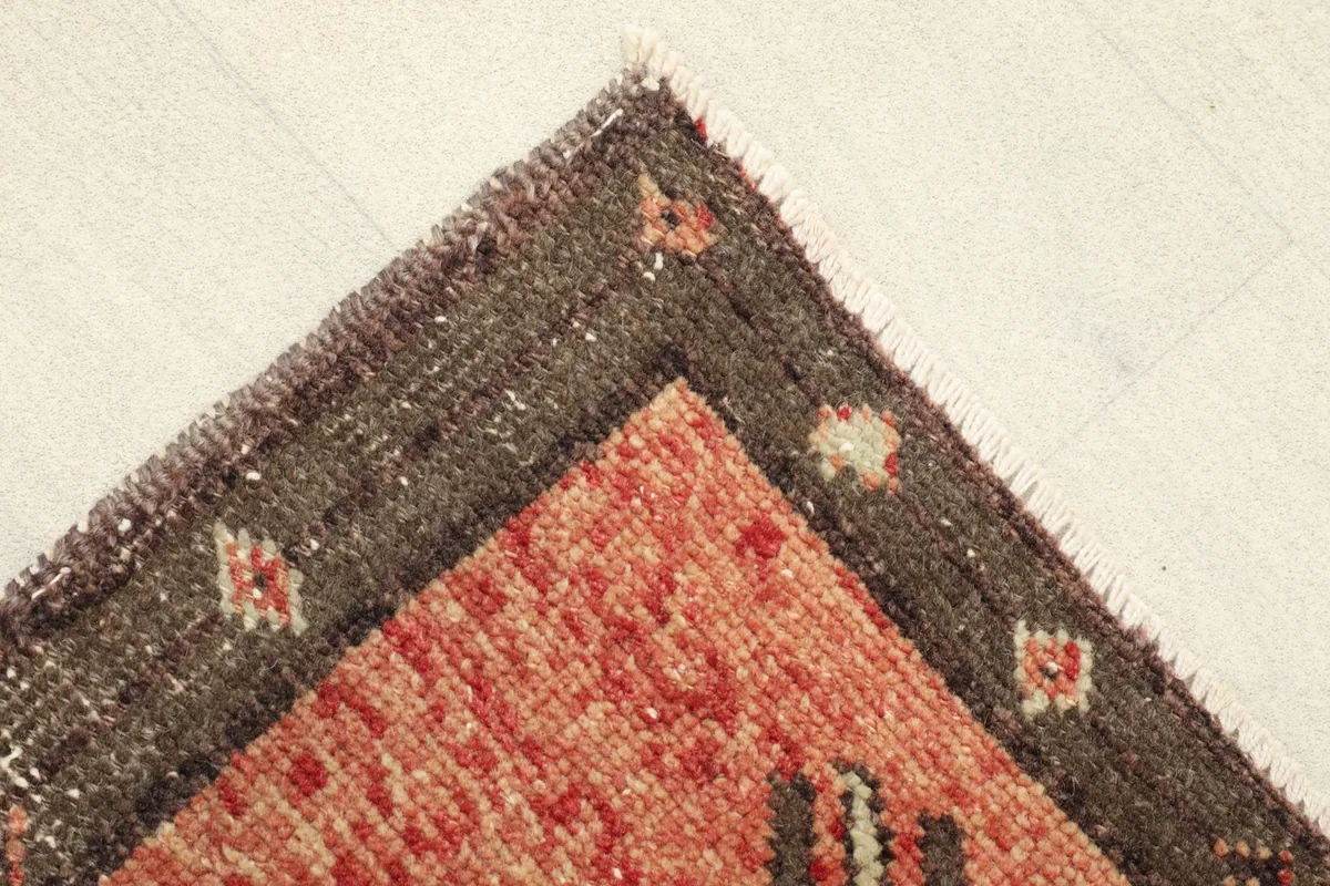 Corner detail showing the brown border and the rust field with some visible wear and patina.