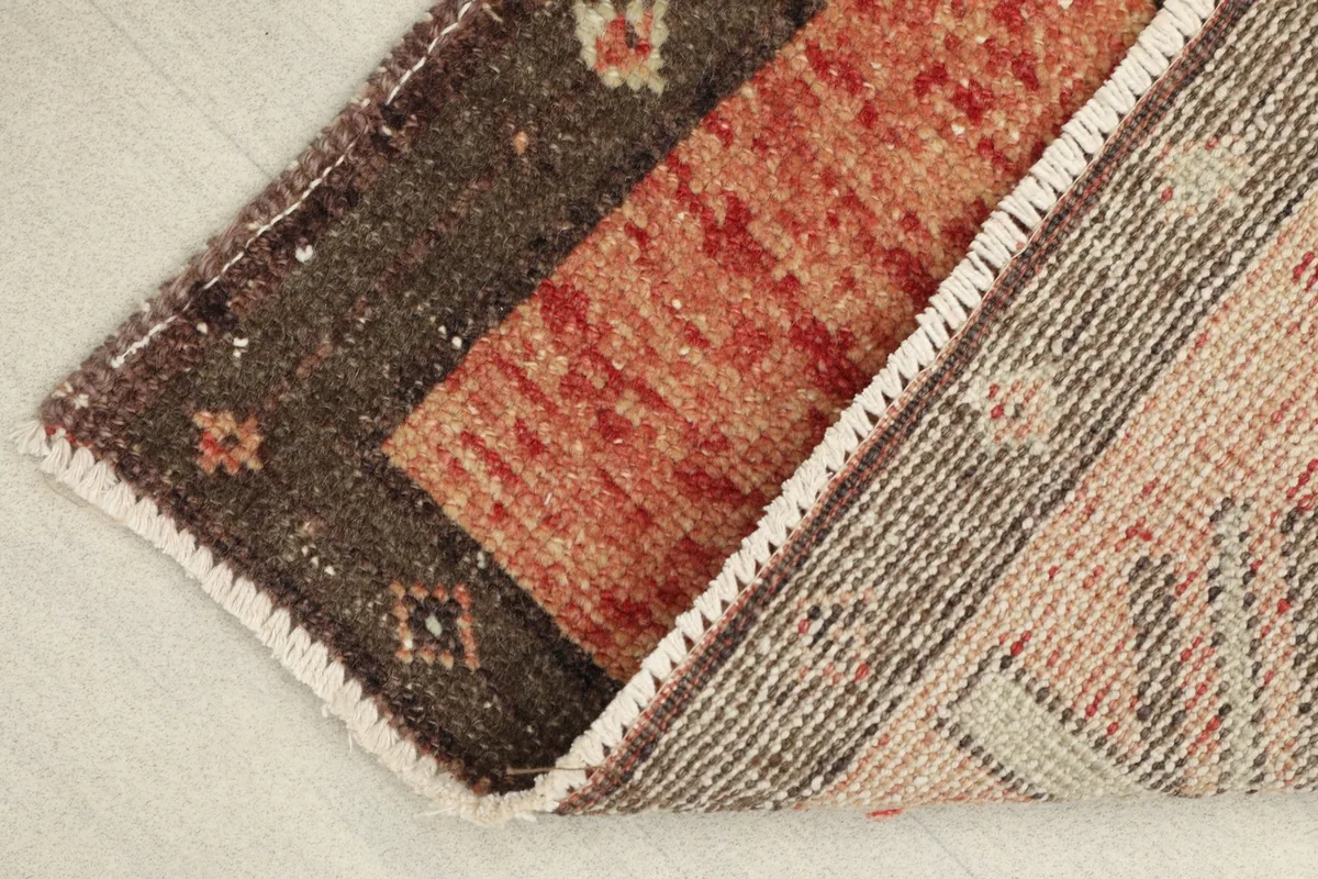 Partial view of the back of the hand-knotted doormat, showing the cotton foundation and wool knots.