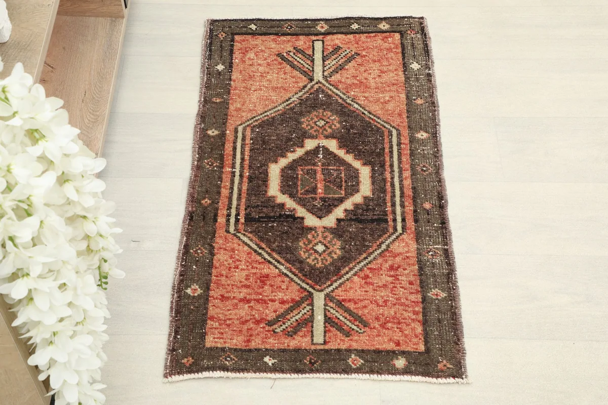 Overhead view of the hand-knotted wool doormat, showcasing its rust field and central brown medallion.