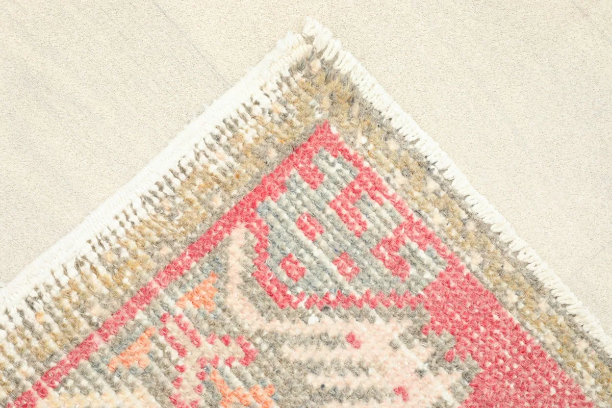 Corner detail showing the beige and gray border pattern and short fringes