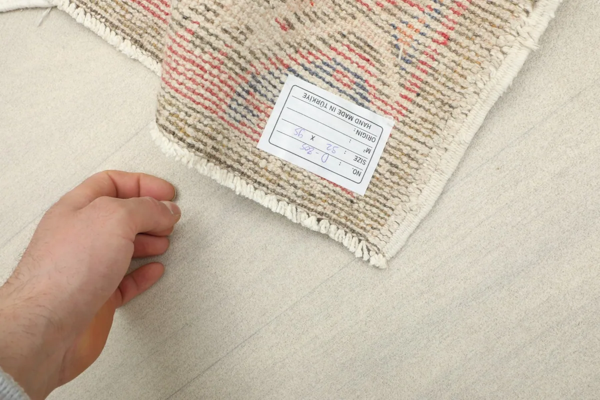 Back of the rug with a label, showing the hand-knotted construction and fringe details