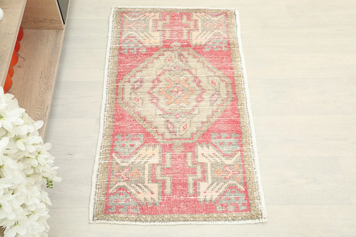Overhead view of the hand-knotted vintage rug, showing its rose and beige geometric patterns