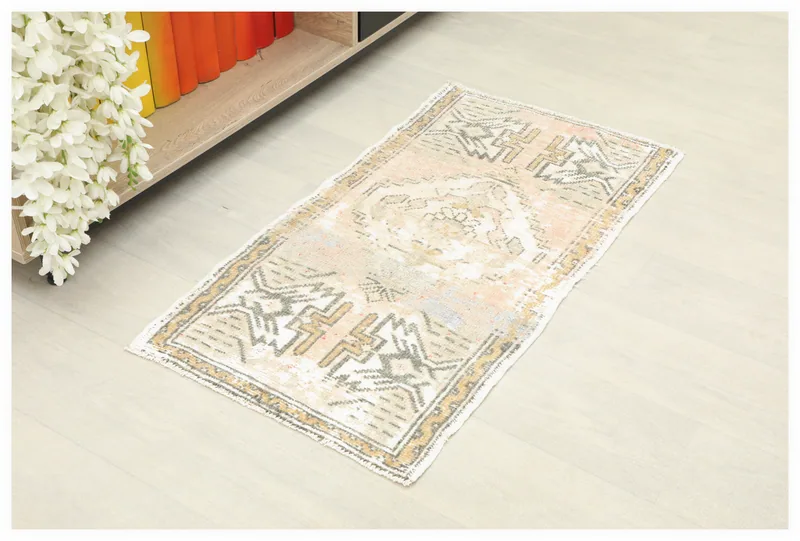 Full top view of the 1'8" x 3'2" vintage Anatolian beige, rose, and gold geometric rug on a light floor.