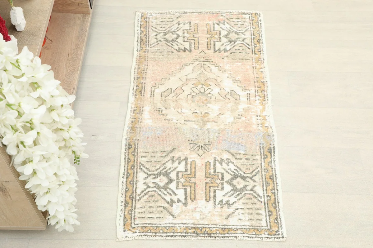 Overhead view of the small hand-knotted wool rug, highlighting its full pattern and faded colors.