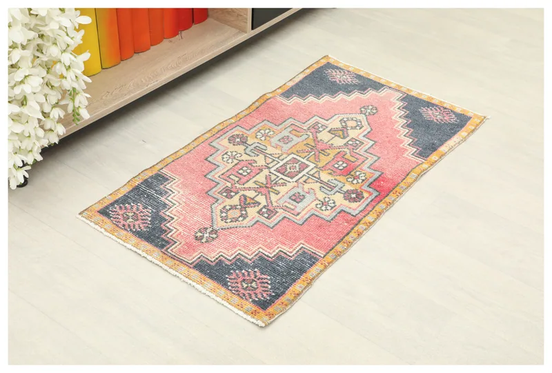 Full top view of the 1'8" x 3'3" rose and navy geometric vintage Anatolian rug on a white floor.