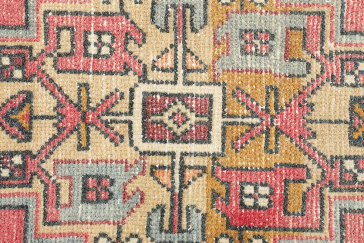 Macro detail of the hand-knotted wool pile, showing the texture and color variations of the geometric pattern.