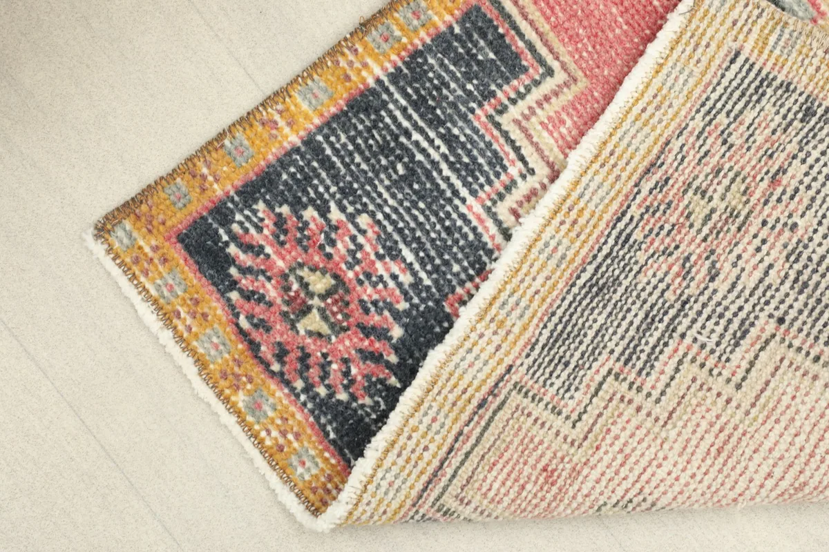 Angled view of the rug with one corner folded back, revealing the reverse side and fringe.