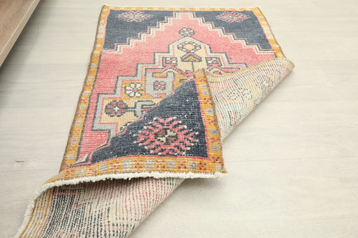 The rug partially folded, showcasing the back of the hand-knotted cotton foundation and wool pile.