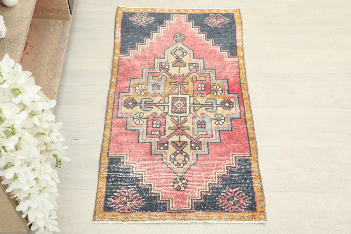 Direct overhead shot of the hand-knotted rose and navy wool rug, showing its full design.