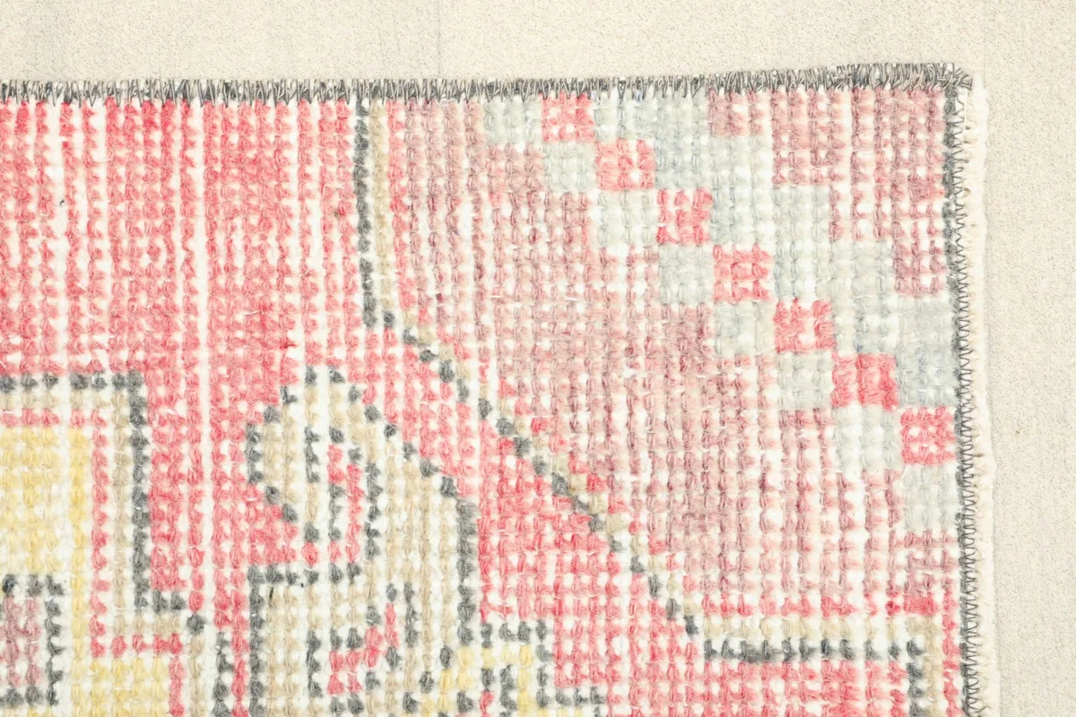 Corner detail of the rug, illustrating the texture of the low pile and the subtle color variations.