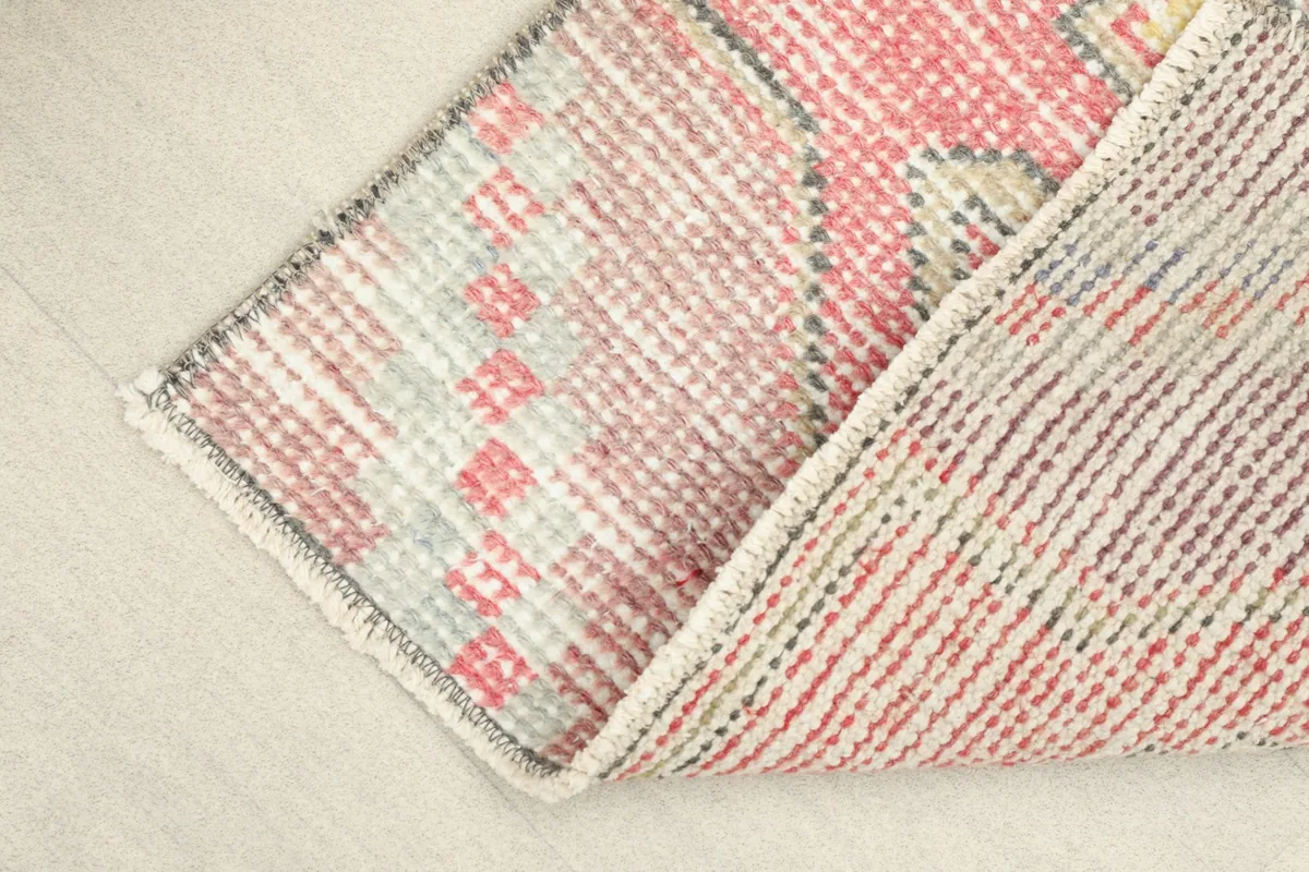 View of the rug's back and partially visible front, revealing the hand-knotted cotton foundation.