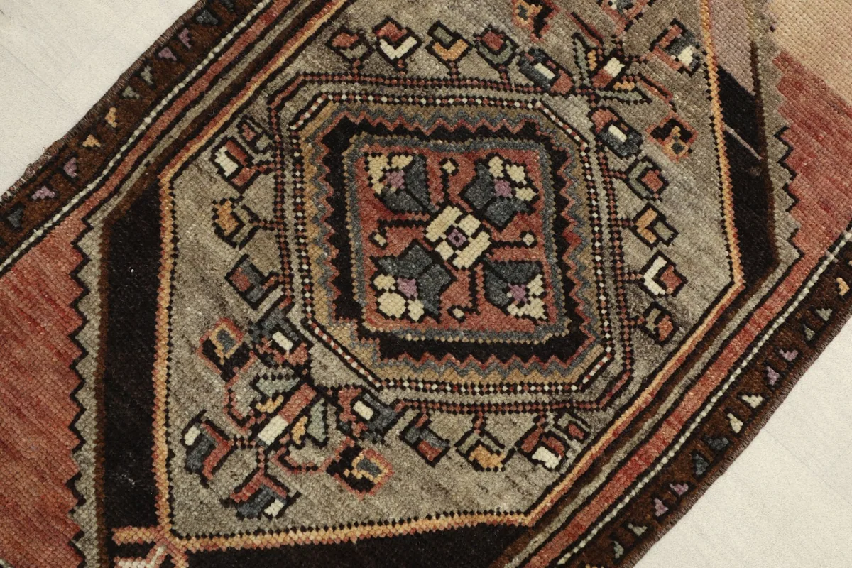 Close-up view of the central gray medallion, highlighting the intricate black, red, ivory, and purple motifs.