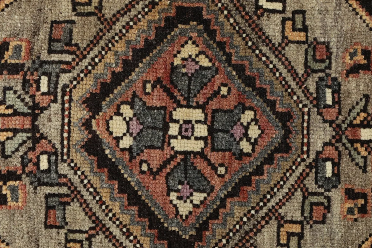 Detailed shot of the central design elements and knotting, showing the texture and color variations of the wool pile.