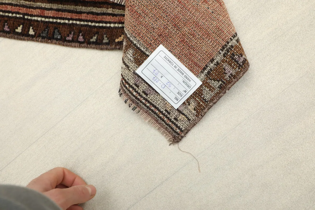 Close-up of the rug's reverse side, displaying the hand-knotted cotton foundation and the vintage label.