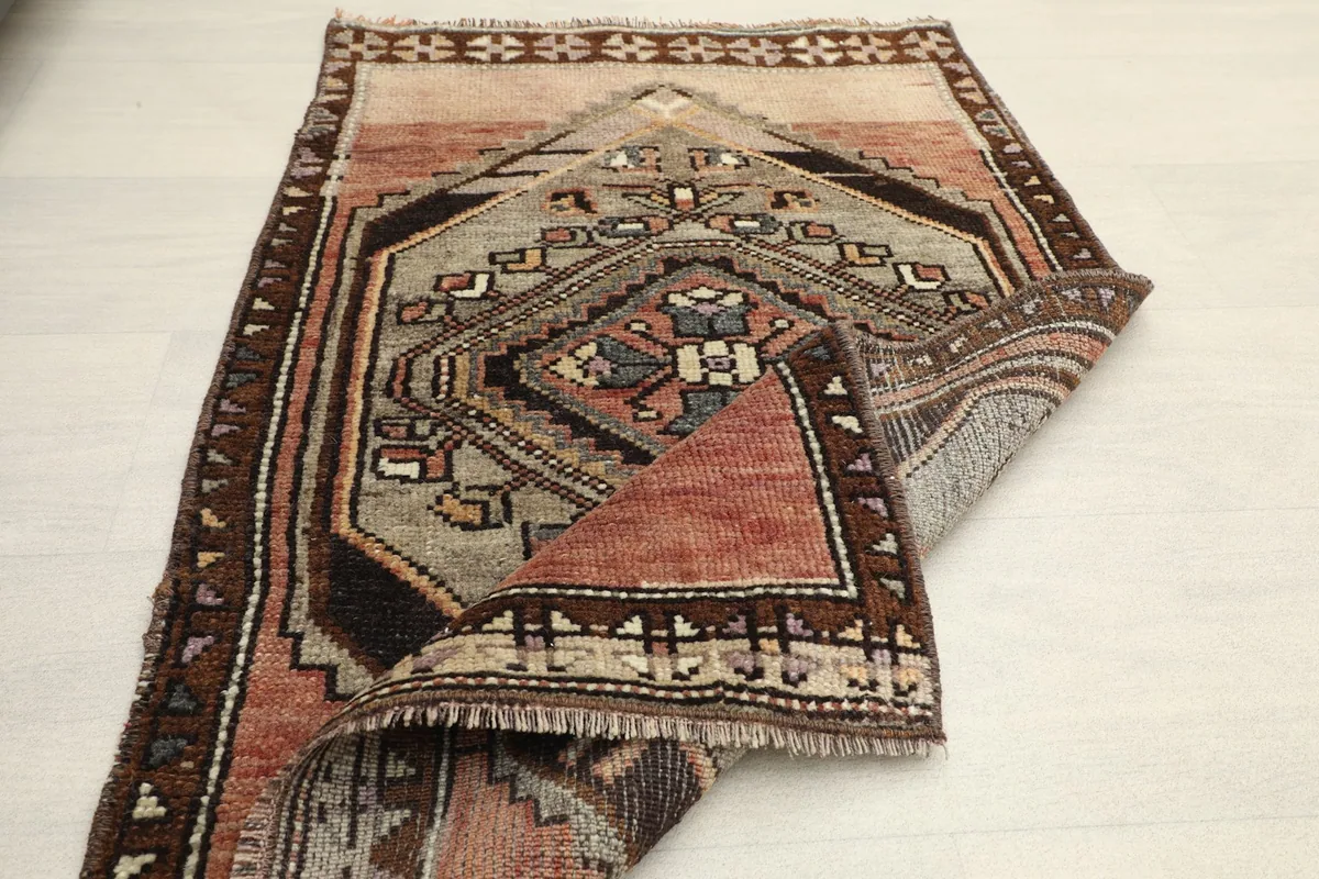 Partial fold of the rug, providing a perspective on its overall size and the texture of the low pile.
