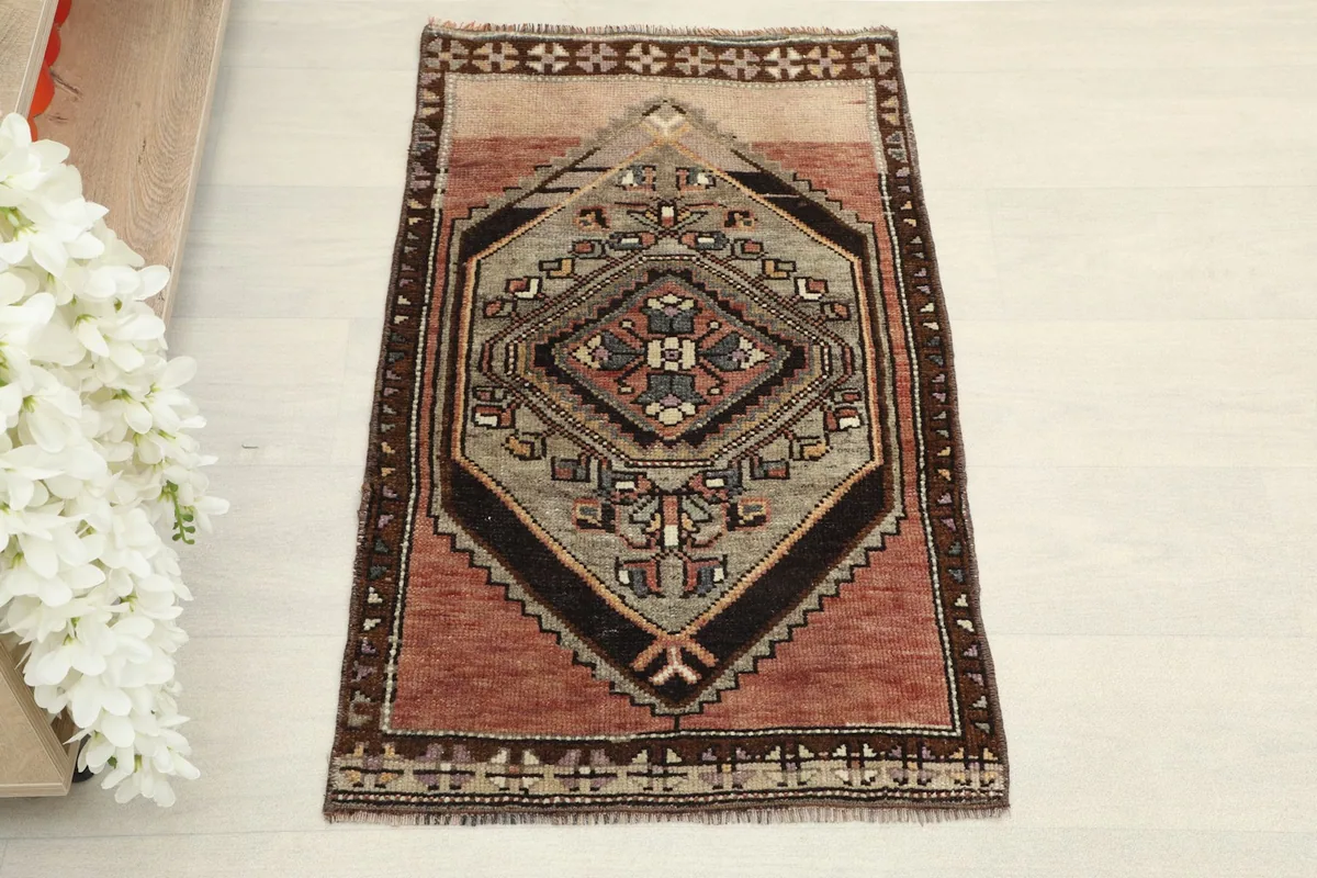 Direct overhead shot of the hand-knotted red and gray rug, showcasing its central geometric medallion and tribal patterns.