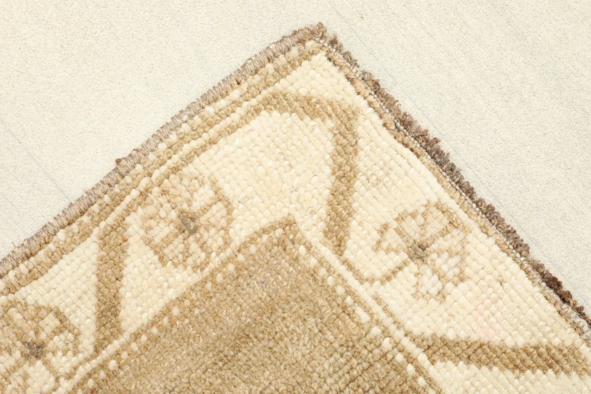 Corner detail showing the ivory border with stylized floral motifs and rug edge