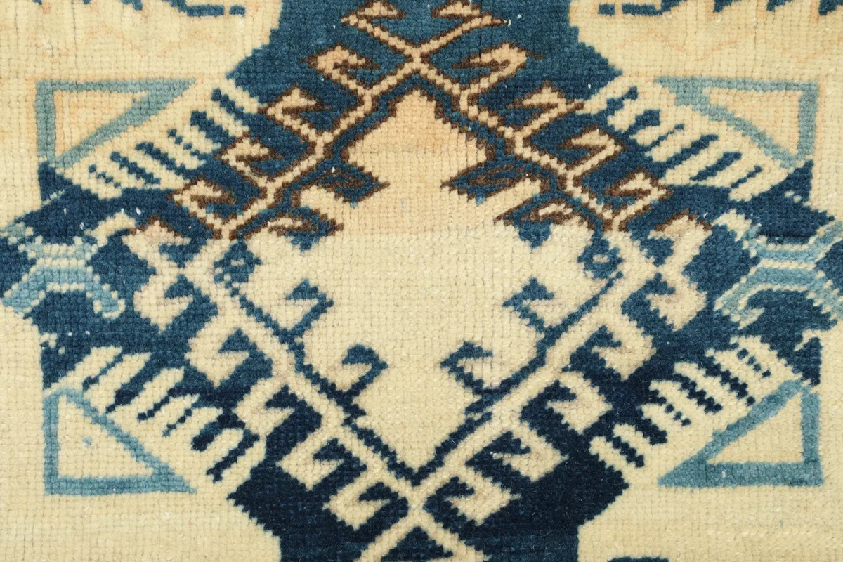 Detailed view of the intricate blue and ivory geometric motifs in the rug's center