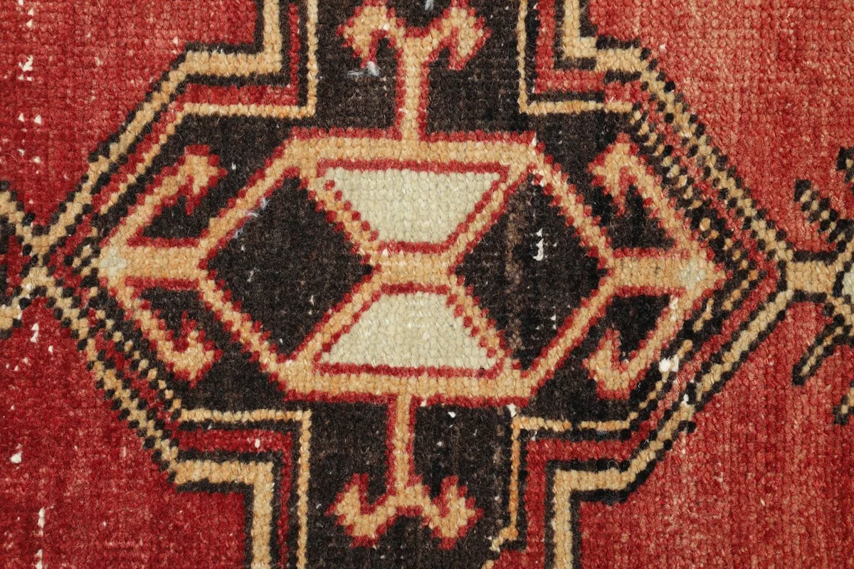 Close-up detail of the central black and ivory geometric motif on the red field.