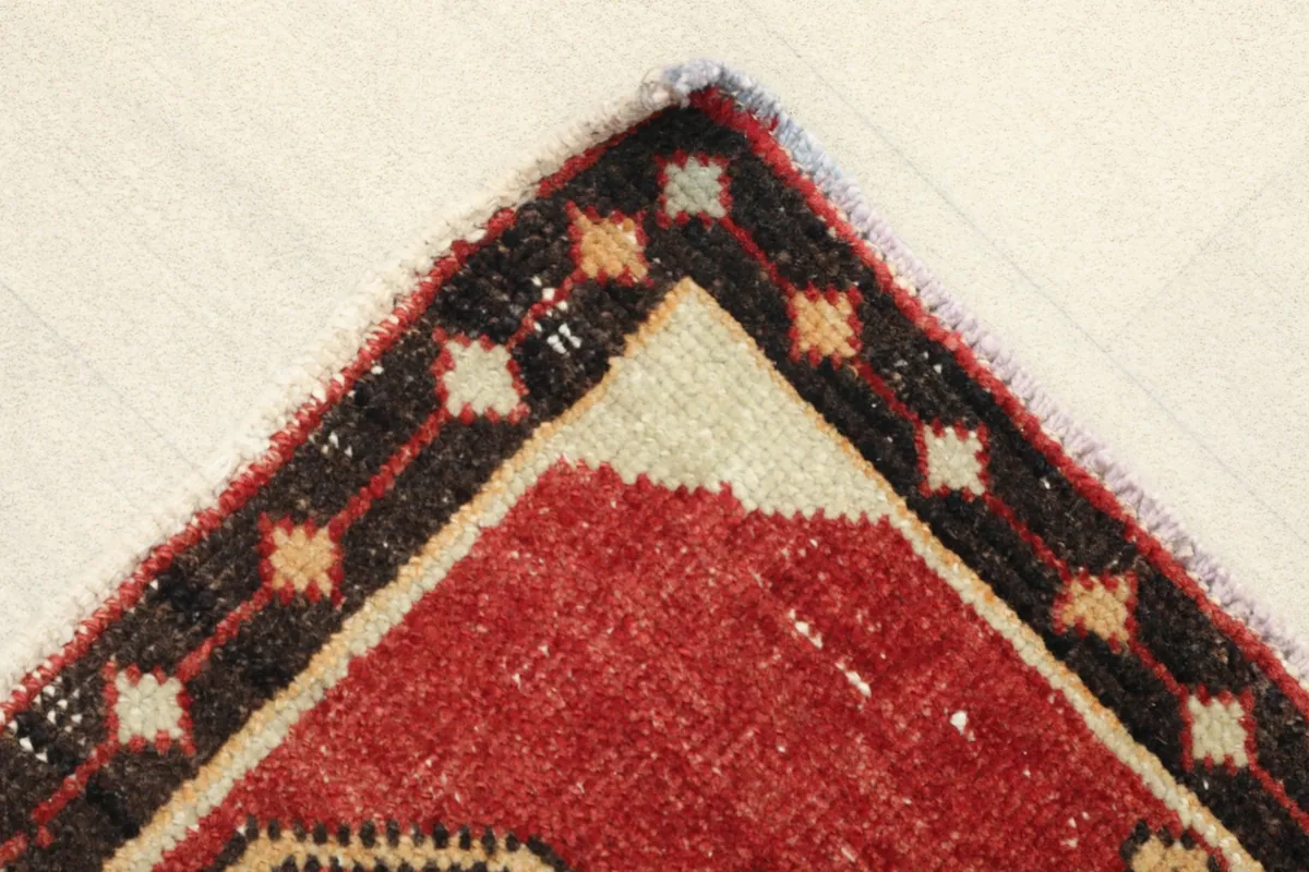 Corner detail showing the black border with small ivory and gold accents and the red field.