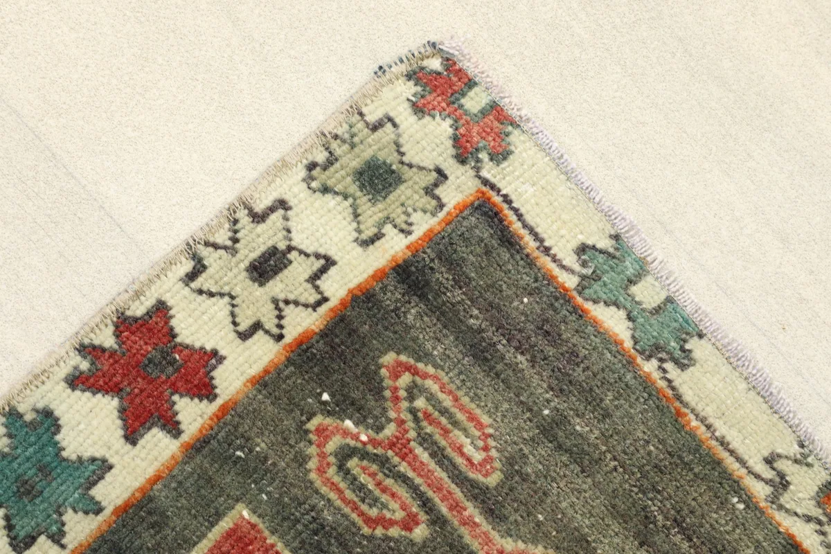 Corner detail showing the cream border with small stylized red, green, and blue floral motifs.