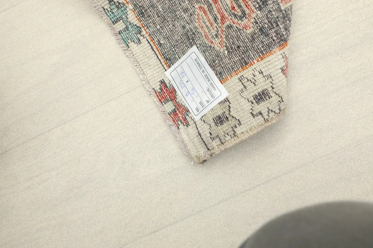 View of the back of the rug with a label, showing the cotton foundation and knotting.