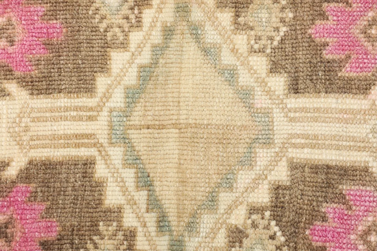 Close-up detail of the central beige and blue diamond motif with brown and pink geometric elements.