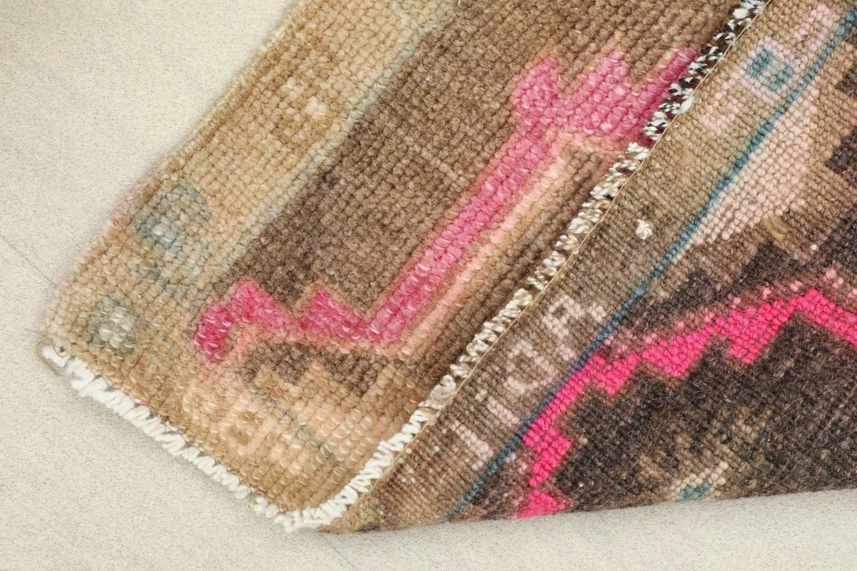 View of the rug folded at a corner, showing the back of the hand-knotted cotton foundation.