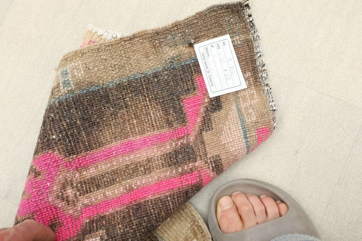 Close-up of the rug's texture and colors with a foot for scale, showing its mini size.