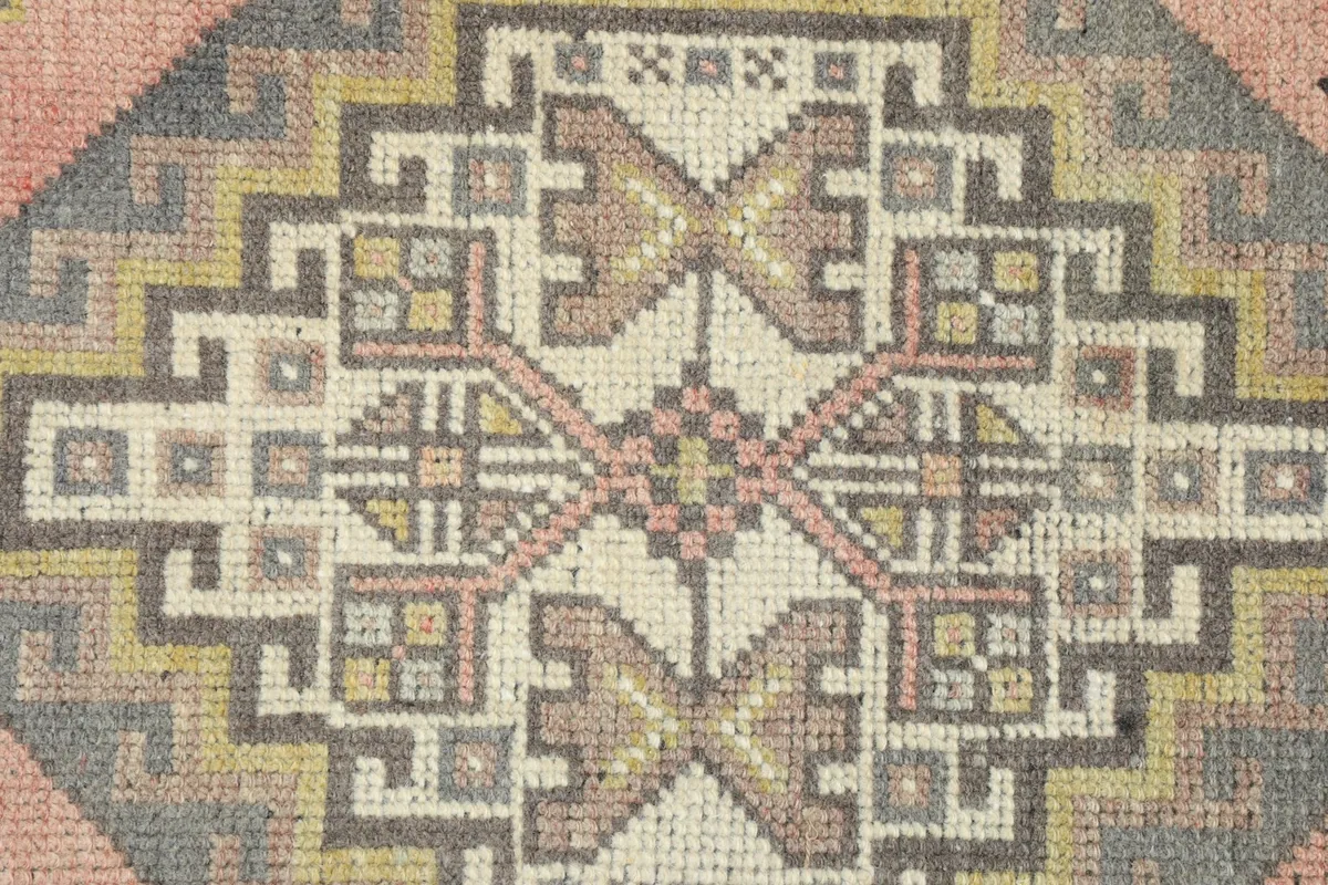 Close-up detail of the intricate geometric knotting and color variations in the rug's center.