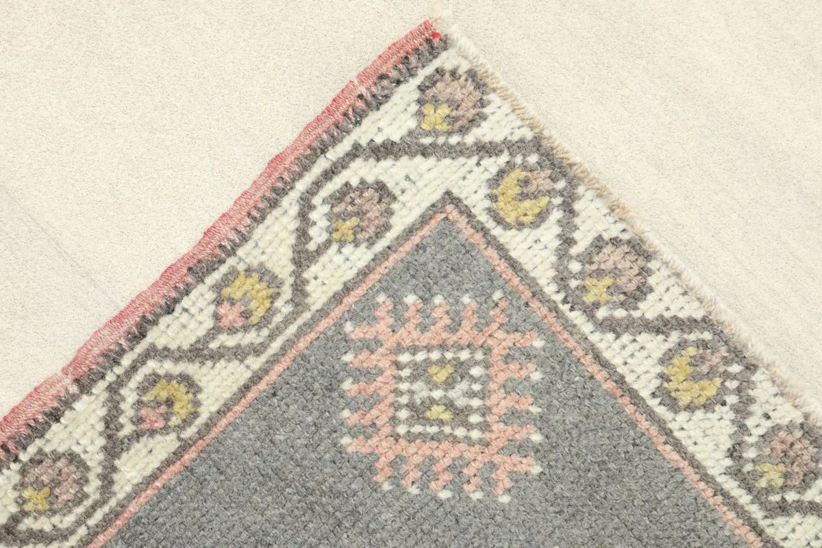 Corner detail showing the ivory border with floral-like motifs and the rose field.