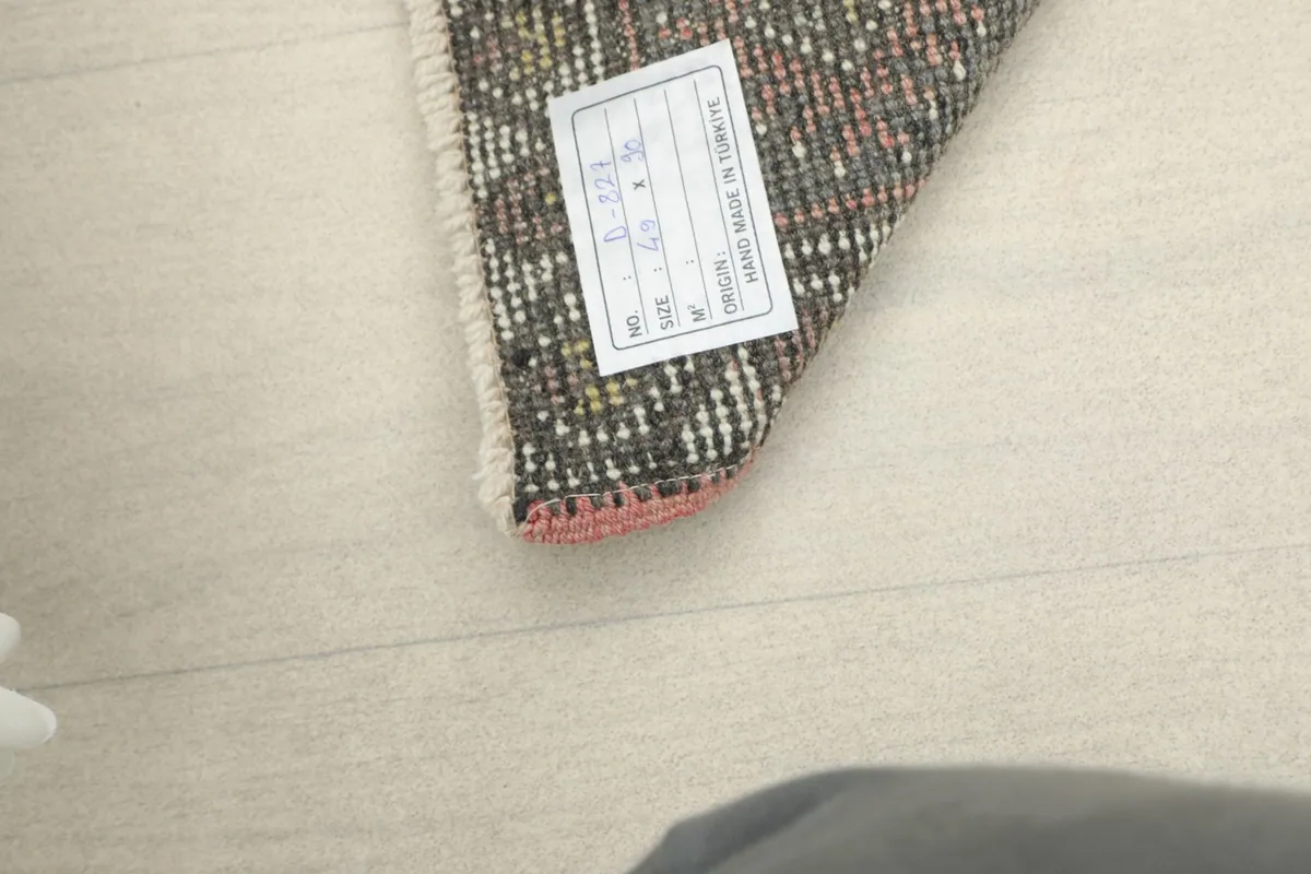 View of the rug's back, revealing the hand-knotted construction and origin label.