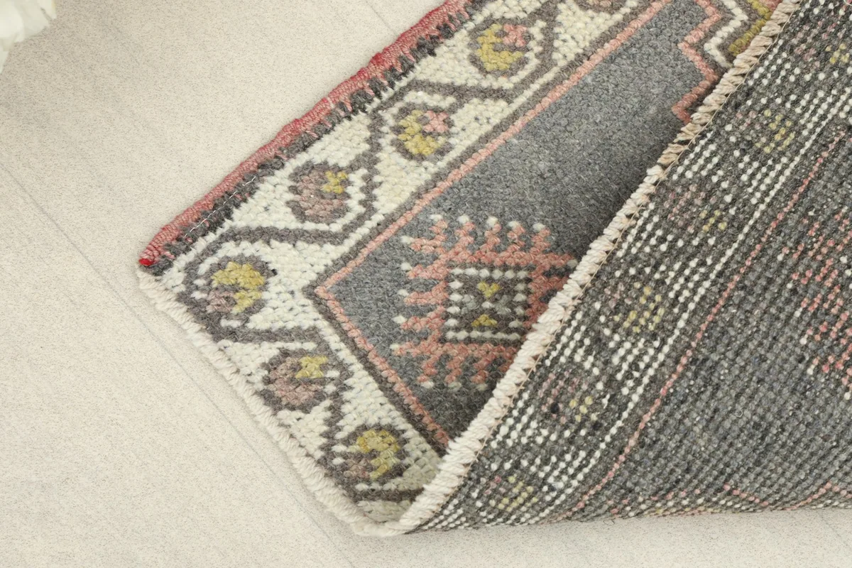Folded corner of the rug, showing the wool pile texture and cotton foundation.